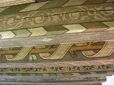 an old painted wooden structure with decorative designs on the top and bottom, along with other decorations