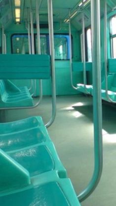 the inside of a subway car with green seats and railings on both sides,