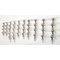 four metal hooks hang on the wall next to each other, one holding several glass tubes