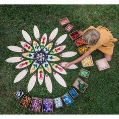 a young boy is sitting on the grass and looking at an array of candies