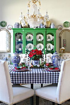 a dining room table set for christmas with blue and white china cabinet in the background