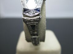 "PLEASE READ ENTIRE DESCRIPTION BEFORE PURCHASING For Sale: (1) Gorgeous Vintage 14k White Gold 1930s Vanburen Diamond & Sapphire Watch Please see pictures for more details! This is a gorgeous watch! The case is marked 14k on the inside. The movement is marked Vanburen Watch Swiss, 2 adjustments, 15 jewels. The watch case features two trillion sapphires at the 12 and 6 position. Above the sapphires is one .03 carat diamond. The watch band is marked 10k gold filled with a deployment clasp. Ea Antique Platinum Watch For Gift, Antique Platinum Watches As Gift, Antique Platinum Watches For Gifts, Antique Platinum Watches Suitable For Gifts, Art Deco Platinum Watch For Anniversary, Art Deco Platinum Anniversary Watch, Heirloom Wedding Watches With Chronometer, Heirloom Chronometer Watches For Wedding, Heirloom Chronometer Watch For Wedding