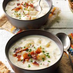 two bowls filled with potato soup on top of a wooden table