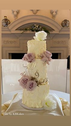 a three tiered wedding cake with purple flowers on the top and white frosting