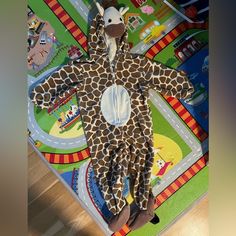 a child's giraffe costume laying on the floor in front of a play mat