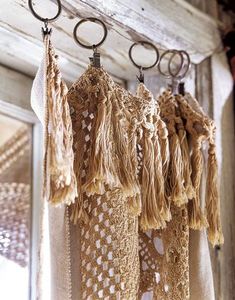 several pieces of crocheted fabric hanging from hooks on a wooden wall in front of a mirror