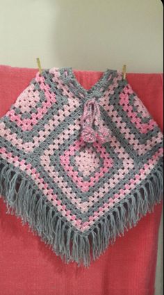 a crocheted shawl hanging on a clothesline with pink and gray colors