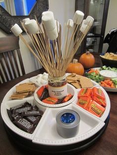 an assortment of candy and marshmallows arranged on a tray with snacks in the background