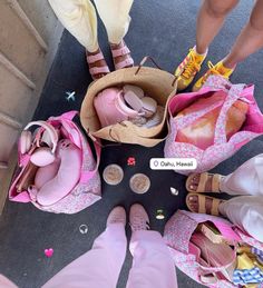 several pairs of pink shoes are arranged in a circle on the ground, with one person's feet sticking out