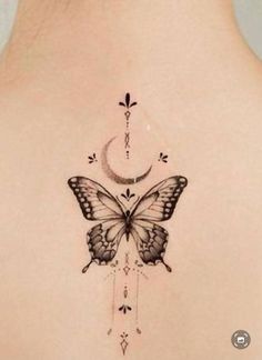 the back of a woman's shoulder with a butterfly and crescent tattoo on it