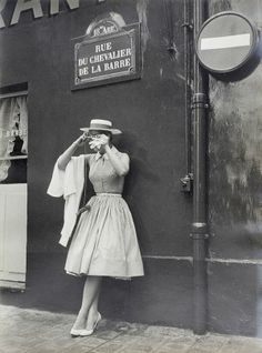 an old photo of a woman leaning against a wall with a hat on her head