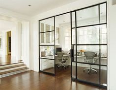 an office with glass walls and wooden flooring in front of the door to another room