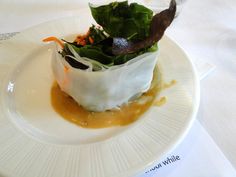 a white plate topped with salad and sauce on top of a bed of lettuce