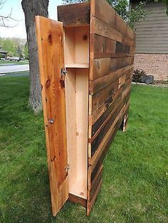 a wooden box sitting in the grass next to a tree and some words on it