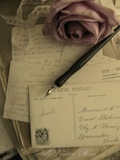 an old envelope with a rose on it and a pen laying next to the envelope