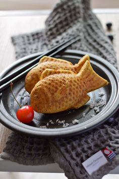 some kind of food on a plate with chopsticks and a cherry in it