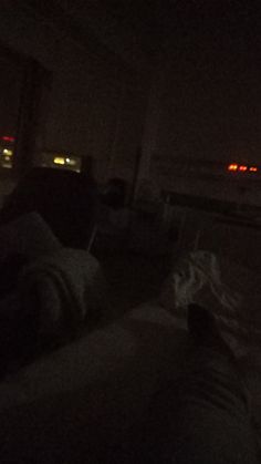 two people are sitting in the dark watching tv