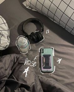 headphones, water bottle and cell phone laying on a bed with black comforter