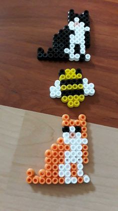 three pieces of bead art sitting on top of a wooden table