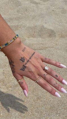 a woman's hand with tattoos on it and two rings in the middle of her left hand