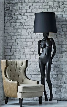 a black mannequin standing next to a chair and lamp