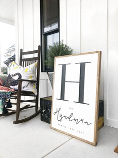 a wooden rocking chair sitting on top of a porch next to a sign that says h