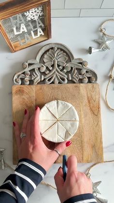 a woman is decorating a piece of wood with white marble and silver decorations on the table