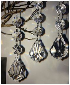 the sun shines through some crystal hanging ornaments on a tree branch in front of a white wall