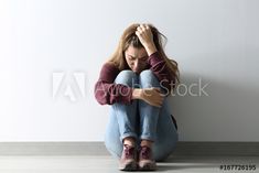 a woman sitting on the floor with her head in her hands