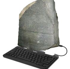 a computer keyboard sitting on top of a stone block with writing on it's side