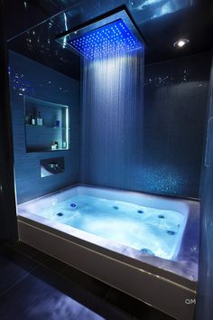 a bathroom with a large tub and blue lights on the shower head is lit up