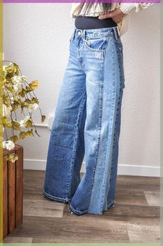 a woman standing in front of a white wall wearing blue jeans