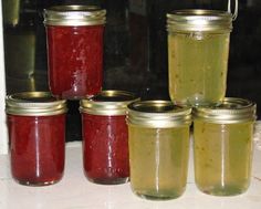 four jars filled with different colored liquid sitting on a counter top next to each other