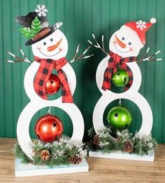 two snowmen are standing next to each other with christmas decorations on their heads and arms