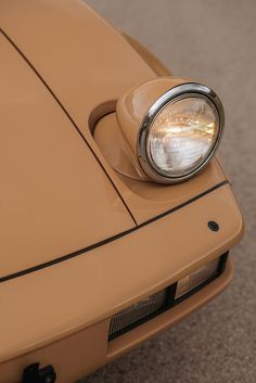 the front end of an orange sports car with a light on it's headlight