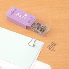 there is a small purple box with some paper clips in front of it on the table