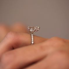 a woman's hand holding an engagement ring with a diamond on top and side