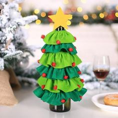 a small christmas tree sitting on top of a table next to a glass of wine