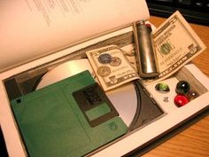 an open laptop computer sitting on top of a wooden desk next to a pile of money