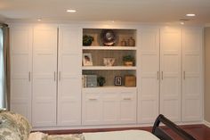 a bedroom with white cupboards and a bed