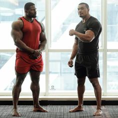 two men standing next to each other in front of a window