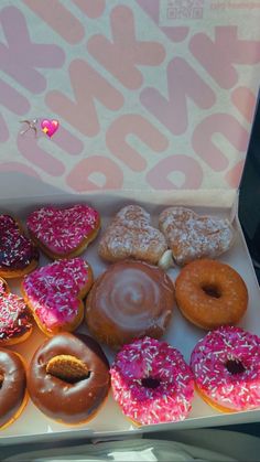 a box filled with lots of different flavored donuts on top of a table