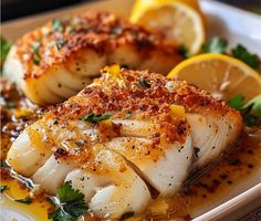 some fish on a white plate with lemons and parsley sprinkled around it