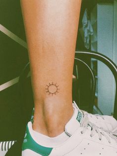 a small sun tattoo on the ankle