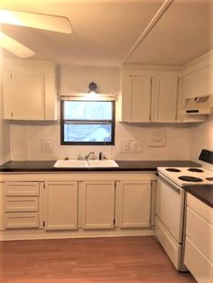 an empty kitchen with white cabinets and black counter tops