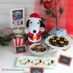 a table topped with chocolate covered treats and a stuffed dog next to a christmas tree