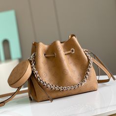 This Bella bucket bag with coin purse is made of Mahina calfskin with a plain weave and Monogram floral pattern surrounded by more than 60,000 custom perforations. Tonal leather trim and hardware complete the overall design. Finished with braided handles and an adjustable, detachable leather shoulder strap.

Dimensions: 19 x 22 x 14 cm Lv Crossbody Bag, Louis Vuitton Yayoi Kusama, Louis Vuitton Capucines, Product Catalogue, Large Cosmetic Bag, Lv Purse, Fendi Peekaboo, Lv Shoes, Medium Handbags