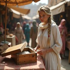 a woman standing next to a wooden box on top of a table with people in the background