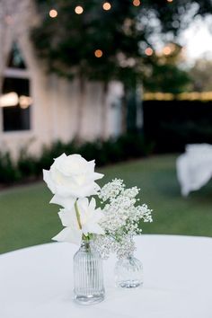 two vases filled with white flowers sitting on top of a table