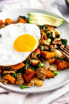 a white plate topped with vegetables and an egg